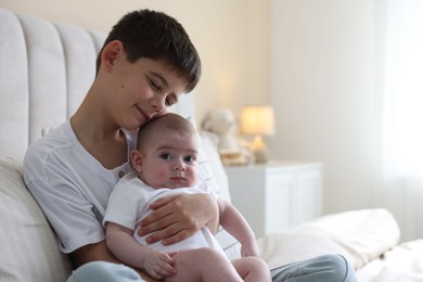 Photo of Cute little brothers sitting on bed at home