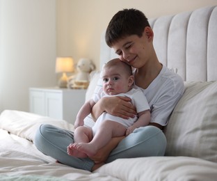 Photo of Cute little brothers sitting on bed at home