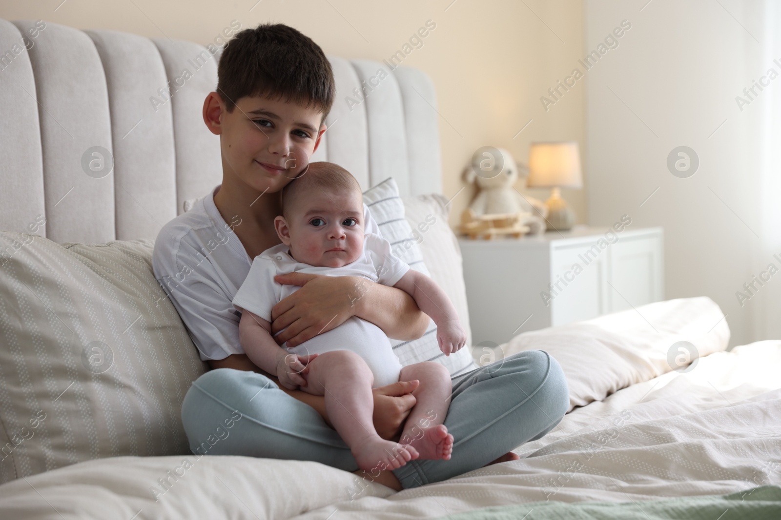 Cute little brothers sitting on bed at home Photo of Cute little brothers sitting on bed at home