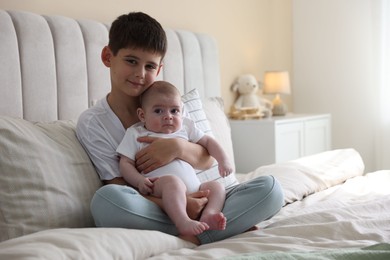 Photo of Cute little brothers sitting on bed at home