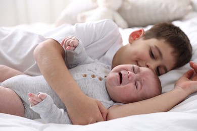 Photo of Cute little brothers on bed at home