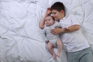 Photo of Cute little brothers on bed, top view. Space for text