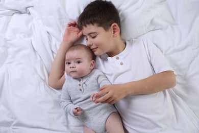 Photo of Cute little brothers on bed, top view