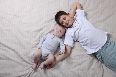 Photo of Cute little brothers on bed, top view