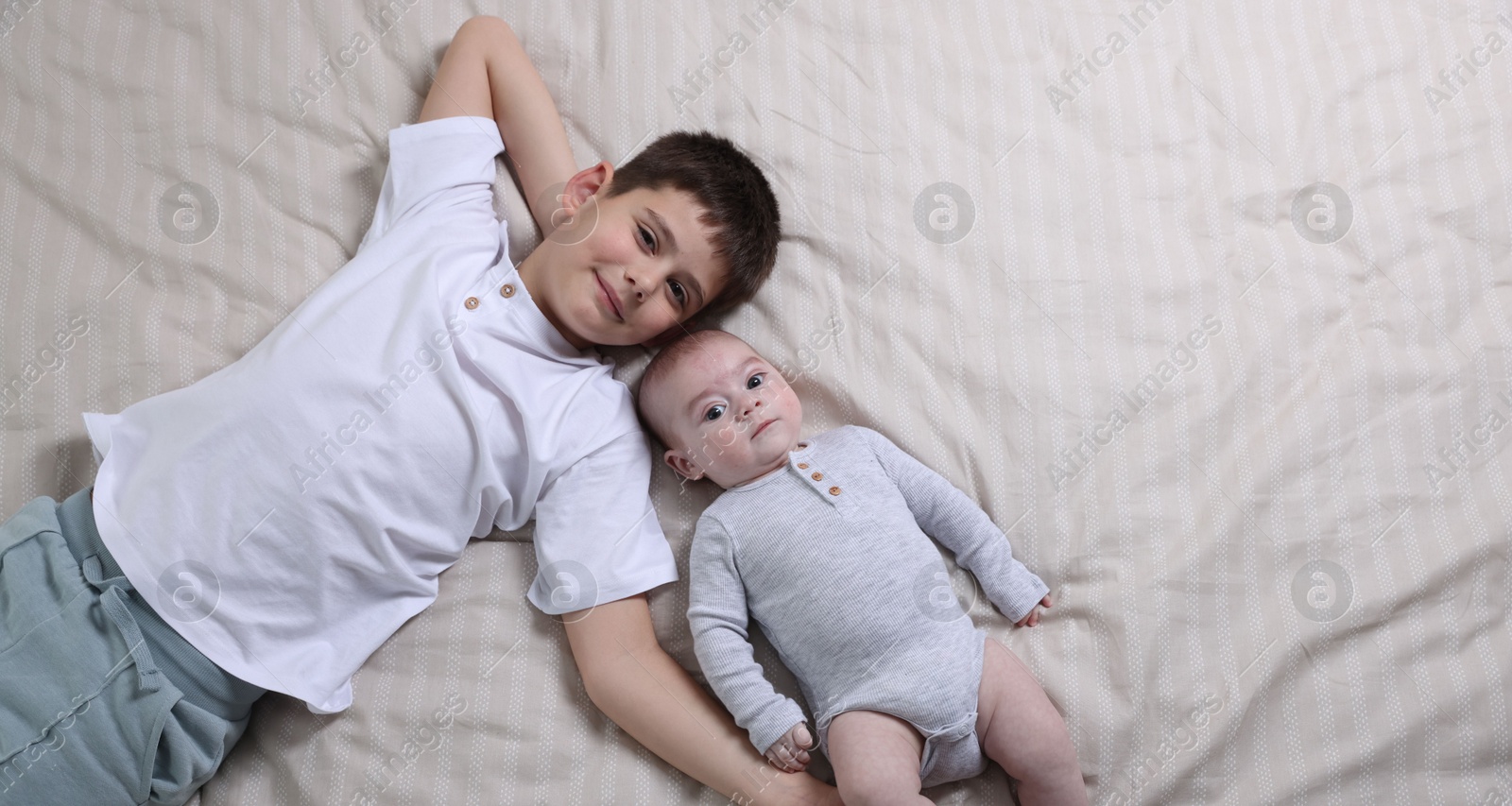 Cute little brothers on bed, top view. Space for text Photo of Cute little brothers on bed, top view. Space for text