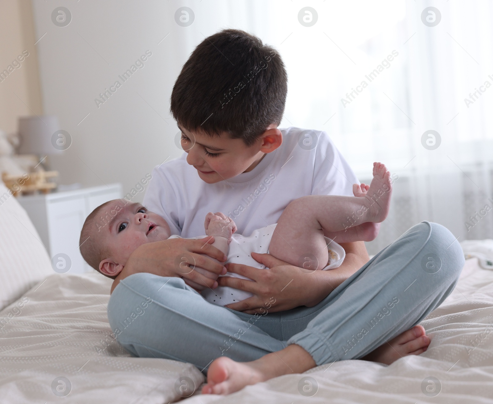 Cute little brothers on bed at home Photo of Cute little brothers on bed at home