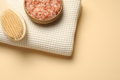Photo of Clean waffle towel, brush and sea salt on beige background, top view. Space for text