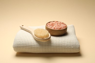 Photo of Clean waffle towel, brush and sea salt on beige background
