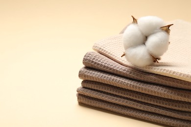 Photo of Clean waffle towels and cotton flower on beige background, closeup. Space for text