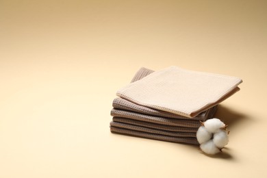 Photo of Clean waffle towels and cotton flower on beige background, space for text