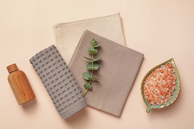 Photo of Clean waffle towels, cosmetic products and eucalyptus branch on beige background, flat lay