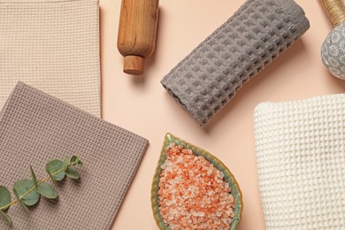 Photo of Clean waffle towels, cosmetic products and eucalyptus branch on beige background, flat lay