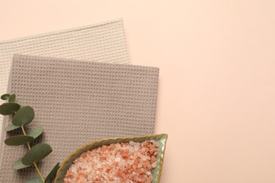 Photo of Clean waffle towels, sea salt and eucalyptus branch on beige background, top view. Space for text