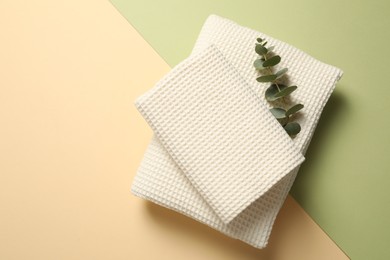 Photo of Clean waffle towels and eucalyptus branch on color background, top view. Space for text