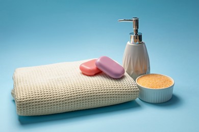 Photo of Clean waffle towel, sea salt and soap on light blue background