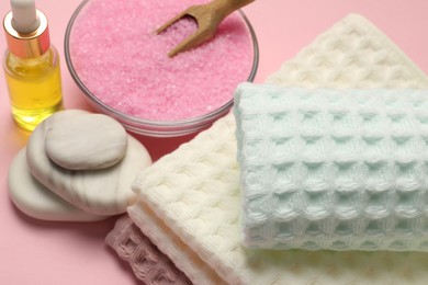 Photo of Clean waffle towels, cosmetic product, sea salt and spa stones on pink background, above view