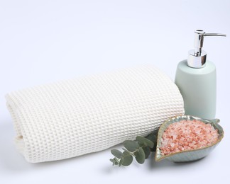 Photo of Clean waffle towel, sea salt, soap and eucalyptus branch isolated on white