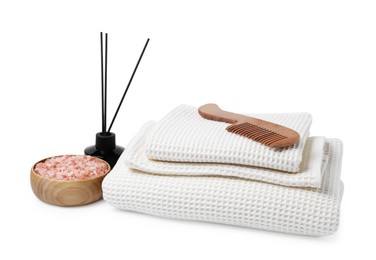 Photo of Clean waffle towels, comb, sea salt and reed aroma diffuser isolated on white