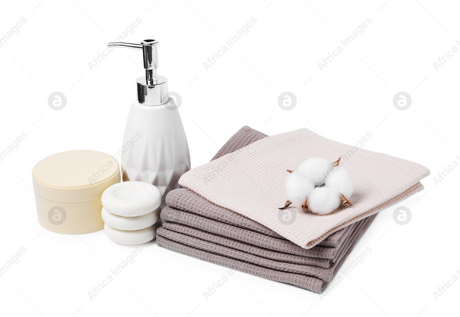 Clean waffle towels, cosmetic products, spa stones and cotton flower isolated on white Photo of Clean waffle towels, cosmetic products, spa stones and cotton flower isolated on white