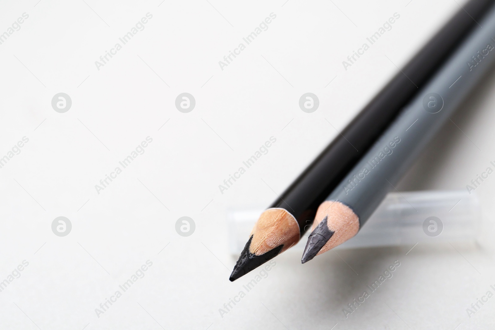 Two different eyebrow pencils on light background, closeup. Space for text Photo of Two different eyebrow pencils on light background, closeup. Space for text