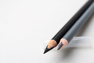 Photo of Two different eyebrow pencils on light background, closeup. Space for text