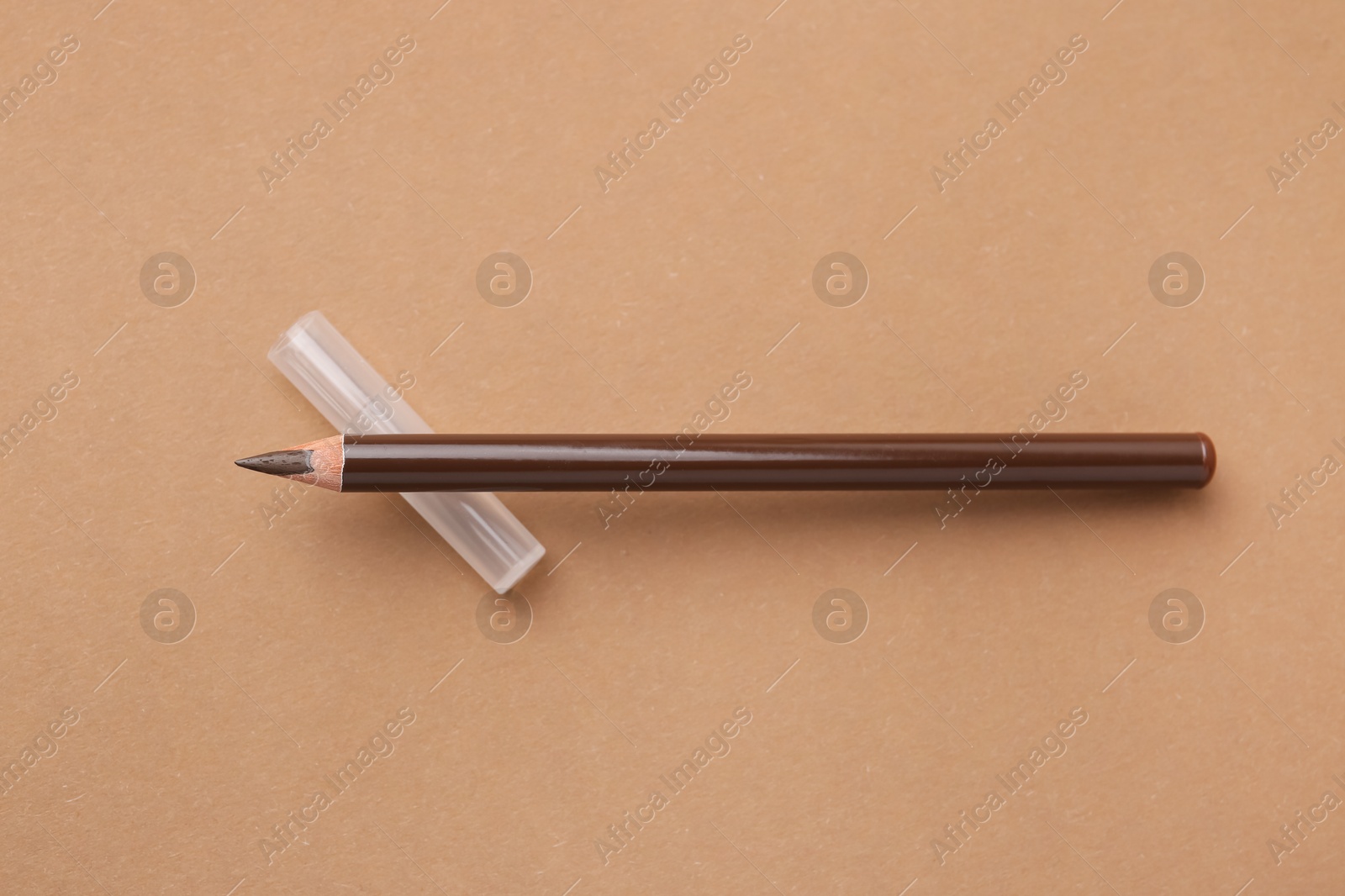 Brown eyebrow pencil on beige background, top view Photo of Brown eyebrow pencil on beige background, top view