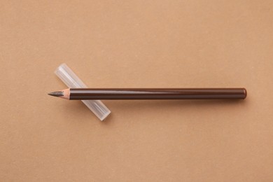 Photo of Brown eyebrow pencil on beige background, top view