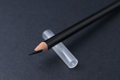Photo of Black eyebrow pencil on dark background, closeup