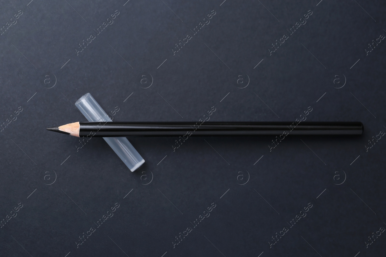Black eyebrow pencil on dark background, top view Photo of Black eyebrow pencil on dark background, top view