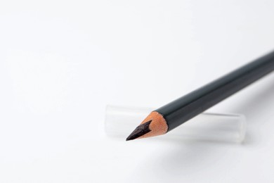 Photo of Black eyebrow pencil on white background, closeup. Space for text