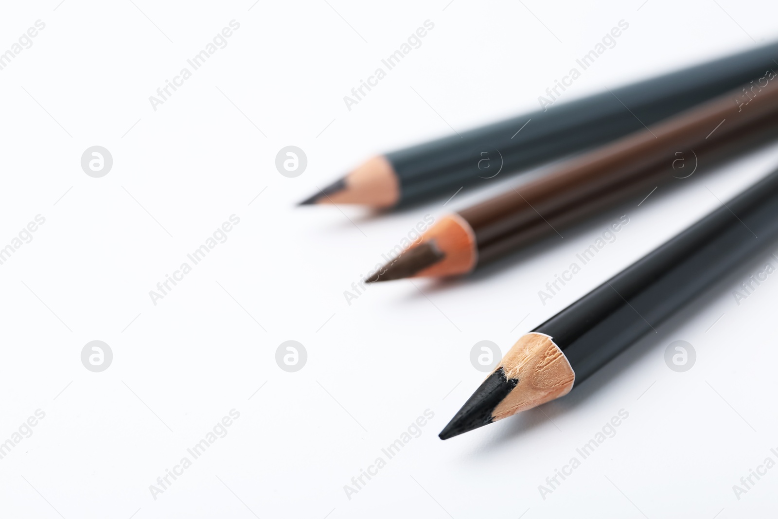 Three different eyebrow pencils on white background, closeup. Space for text Photo of Three different eyebrow pencils on white background, closeup. Space for text