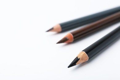 Photo of Three different eyebrow pencils on white background, closeup. Space for text