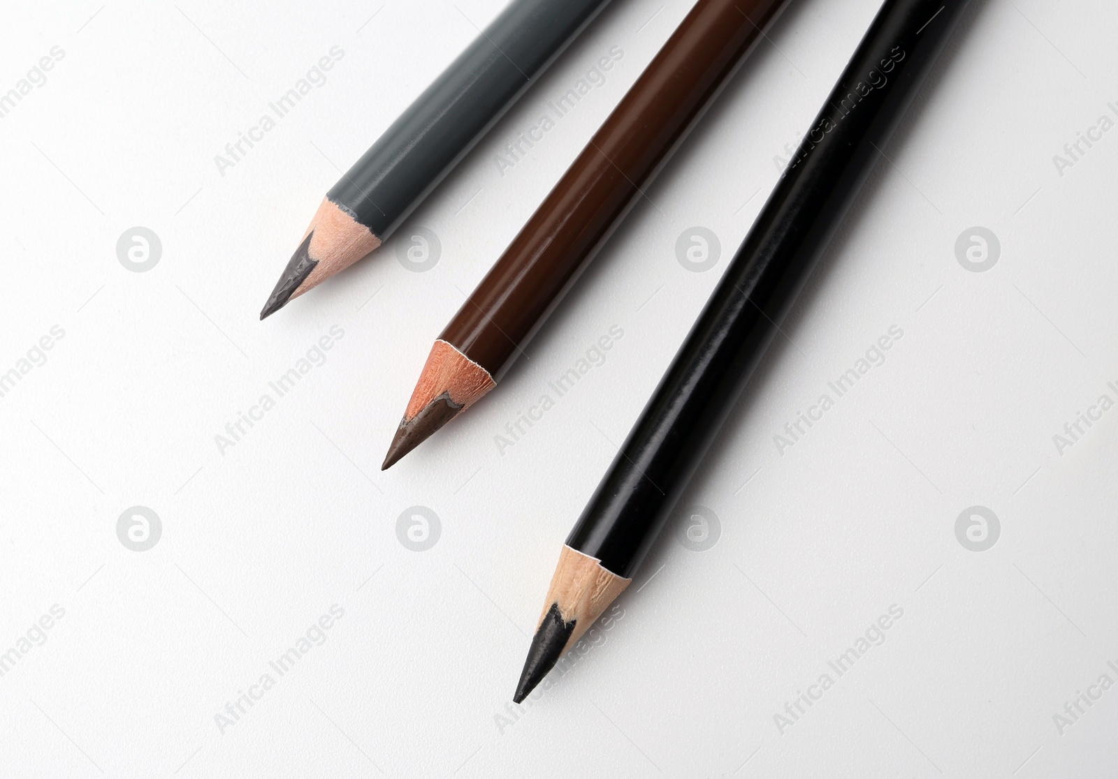 Three different eyebrow pencils on white background, top view Photo of Three different eyebrow pencils on white background, top view