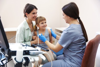 Photo of Sonographer conducting ultrasound examination of girl's heart. Mother and daughter having appointment with doctor in clinic
