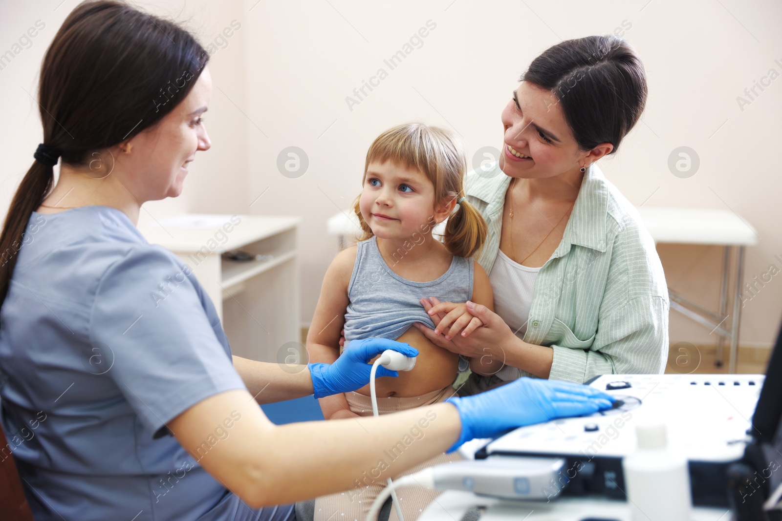 Sonographer conducting little girl's abdominal ultrasound examination. Mother and daughter having appointment with doctor in clinic Photo of Sonographer conducting little girl's abdominal ultrasound examination. Mother and daughter having appointment with doctor in clinic