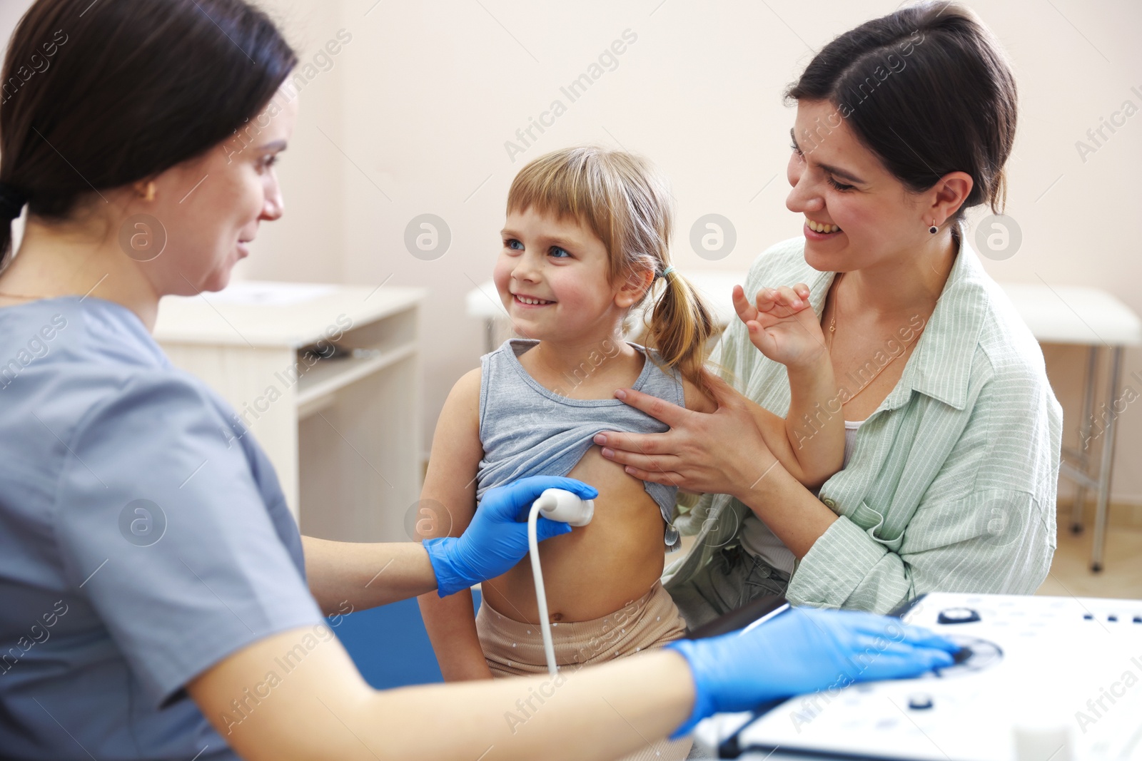 Sonographer conducting little girl's abdominal ultrasound examination. Mother and daughter having appointment with doctor in clinic Photo of Sonographer conducting little girl's abdominal ultrasound examination. Mother and daughter having appointment with doctor in clinic
