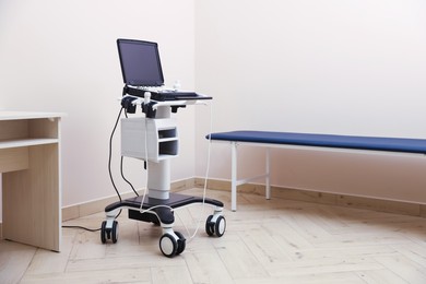 Photo of Modern ultrasound machine and examination bed in clinic