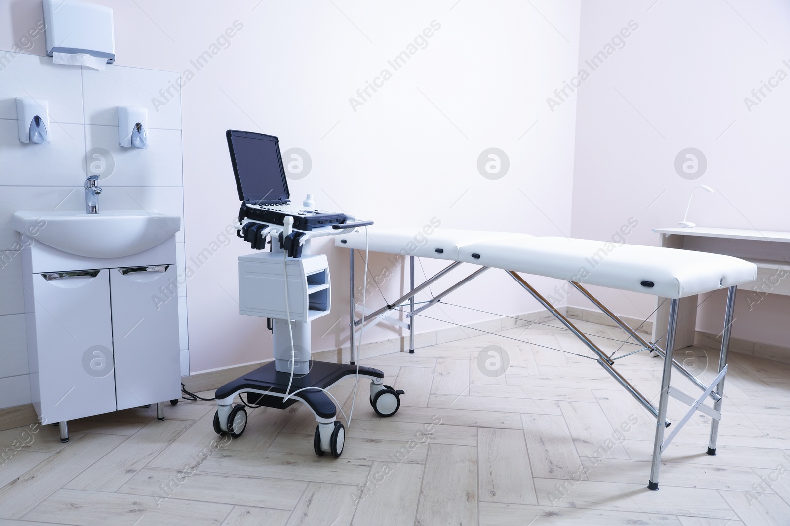 Modern ultrasound machine, sink and examination bed in clinic Photo of Modern ultrasound machine, sink and examination bed in clinic