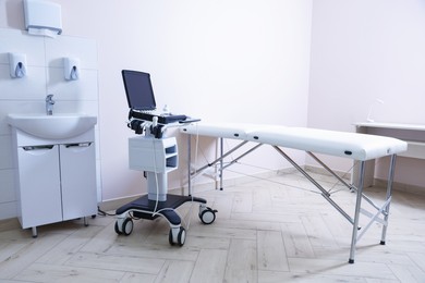 Photo of Modern ultrasound machine, sink and examination bed in clinic