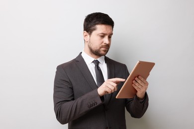 Photo of Handsome businessman using tablet on light grey background