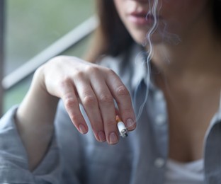 Photo of Woman smoking cigarette indoors, selective focus. Bad habit
