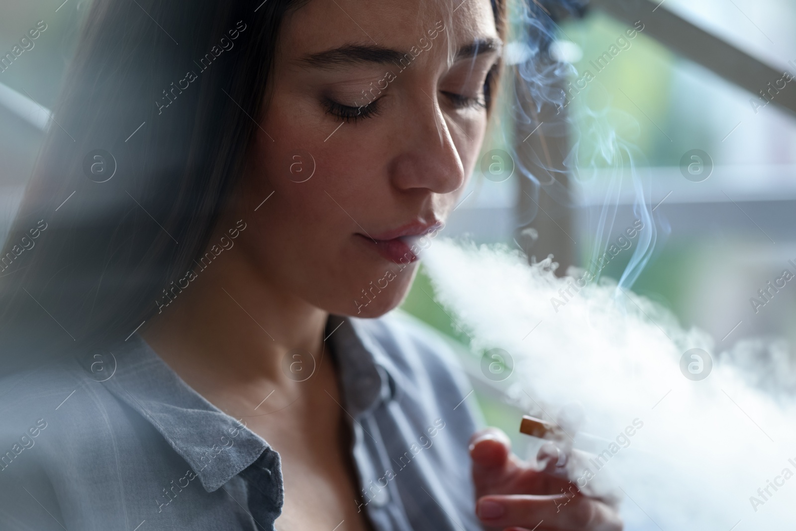 Woman smoking cigarette indoors, closeup. Bad habit Photo of Woman smoking cigarette indoors, closeup. Bad habit