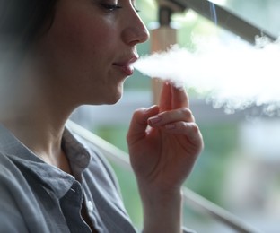 Photo of Woman smoking cigarette indoors, closeup. Bad habit