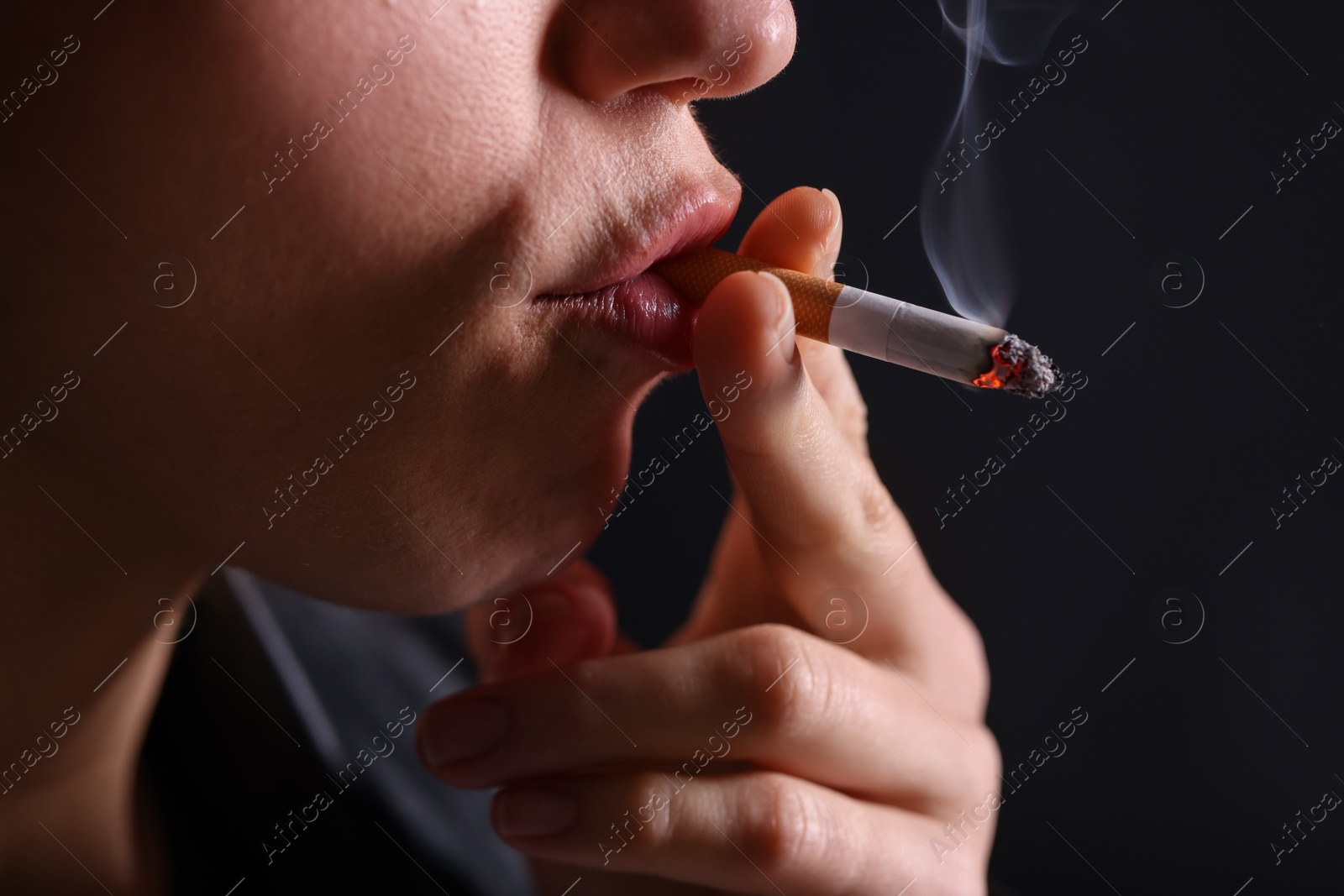 Woman smoking cigarette on black background, closeup Photo of Woman smoking cigarette on black background, closeup