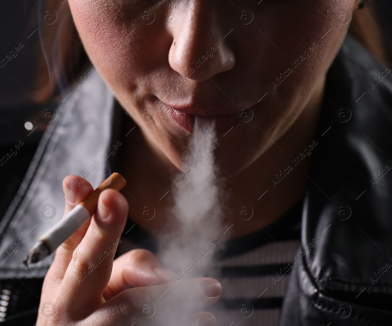 Woman smoking cigarette on black background, closeup Photo of Woman smoking cigarette on black background, closeup