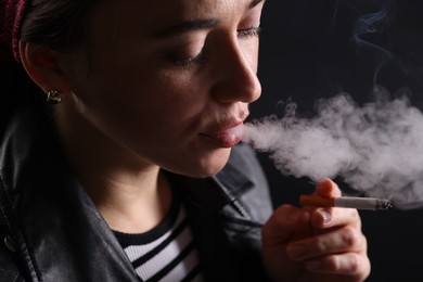 Photo of Woman smoking cigarette on black background, closeup