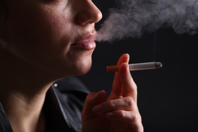 Photo of Woman smoking cigarette on black background, closeup