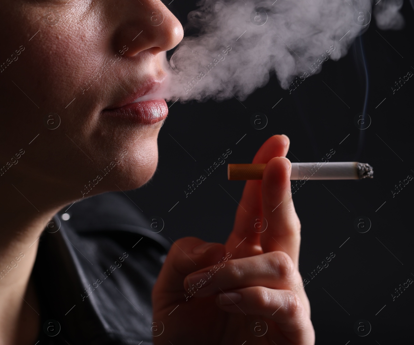 Woman smoking cigarette on black background, closeup Photo of Woman smoking cigarette on black background, closeup