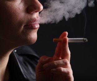 Photo of Woman smoking cigarette on black background, closeup