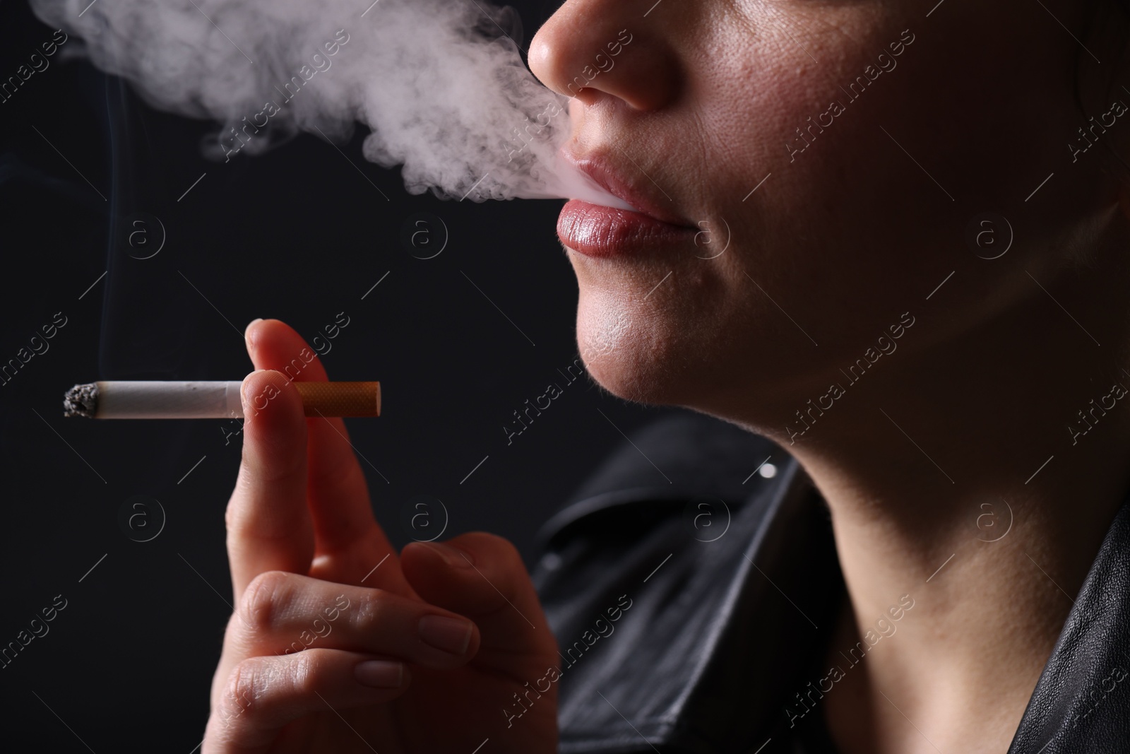 Woman smoking cigarette on black background, closeup Photo of Woman smoking cigarette on black background, closeup